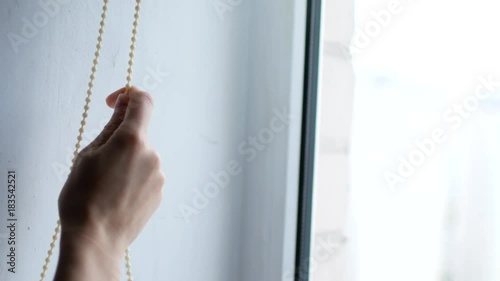 A woman's hand opens the blinds on the window photo