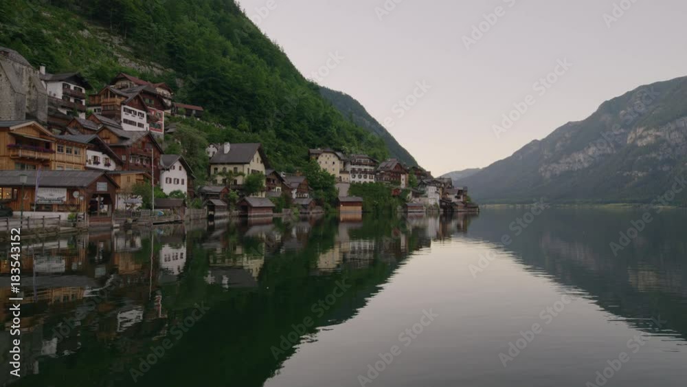 Wide shot of reflection of mountain and houses in lake / Hallstatt, Austria Wide shot of reflection of mountain and houses in lake / Hallstatt, Austria