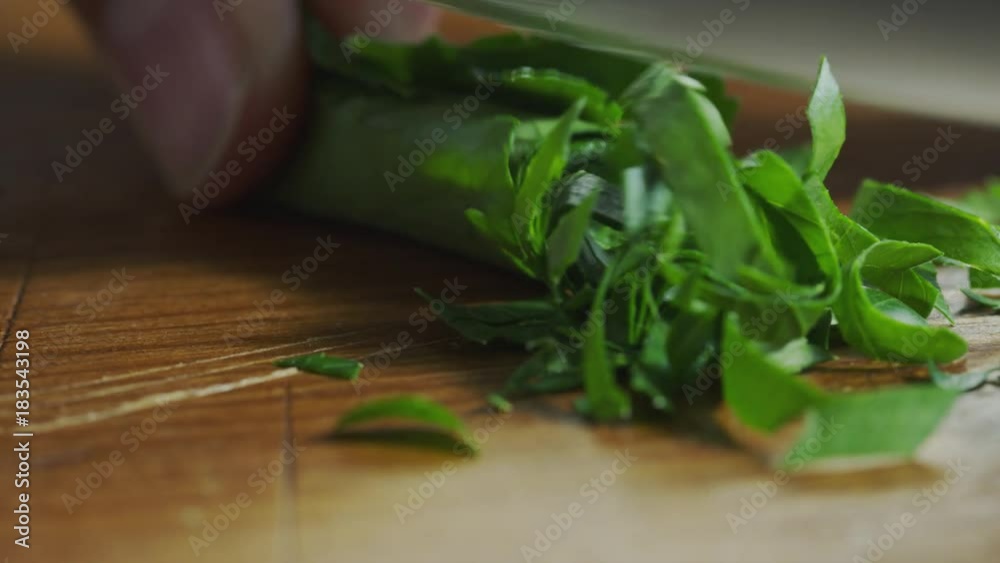 Close up of knife chopping basil leaf on cutting board / Cedar Hills, Utah, United States
