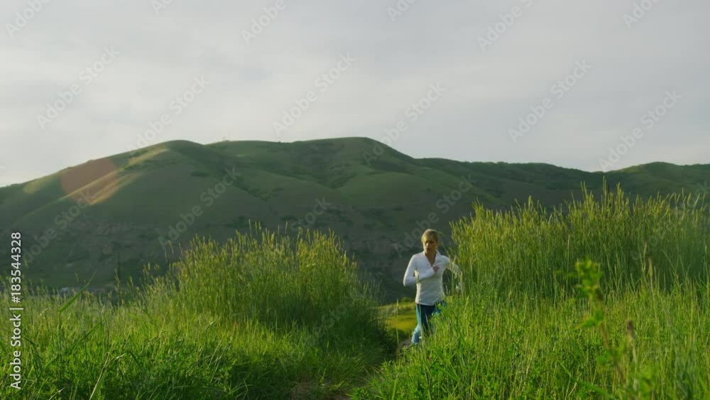 Couple running up hill in green rolling landscape / Salt Lake City, Utah, United States Couple running up hill in green rolling landscape / Salt Lake City, Utah, United States