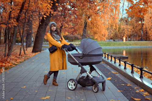 young girl in an autumn park with a baby stroller in moscow, russia