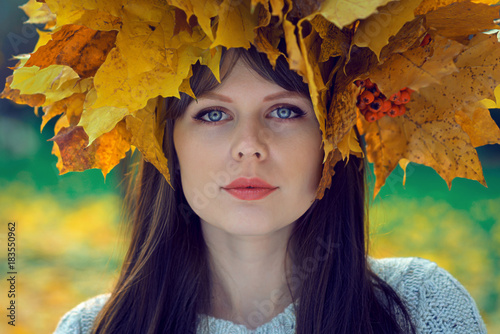 portrait of a young girl with a wreath of leaves on her head in an autumn park in moscow, russia
