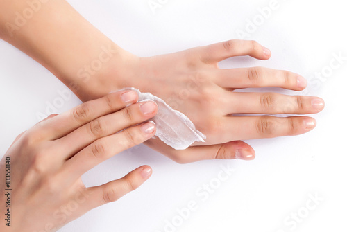 Young woman applying cream on beautiful and manicured hands