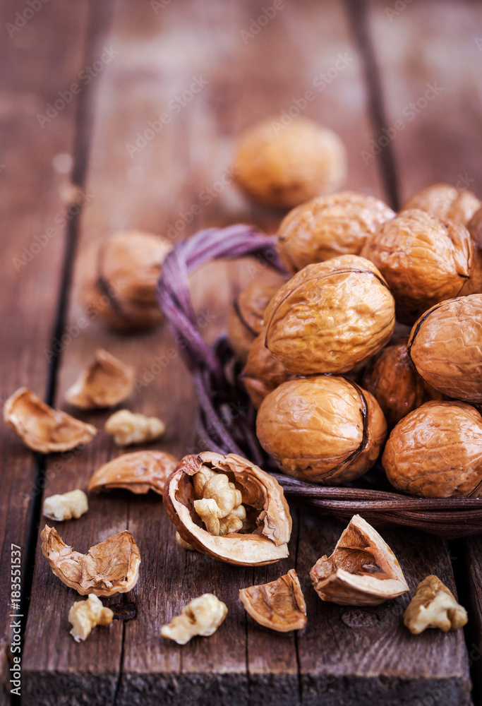 Whole walnuts in basket on rustic old wooden table Whole walnuts in basket on rustic old wooden table