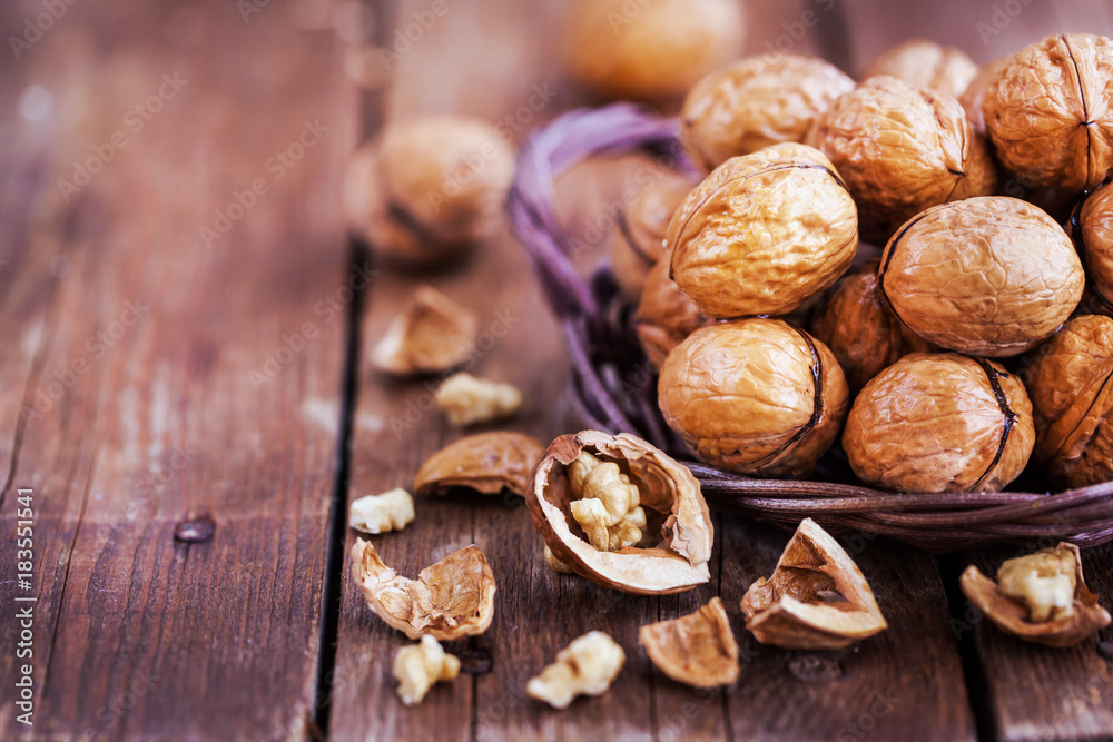 Whole walnuts in basket on rustic old wooden table Whole walnuts in basket on rustic old wooden table
