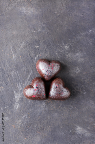 Chocolate candies in the shape of heart on a gray background.
