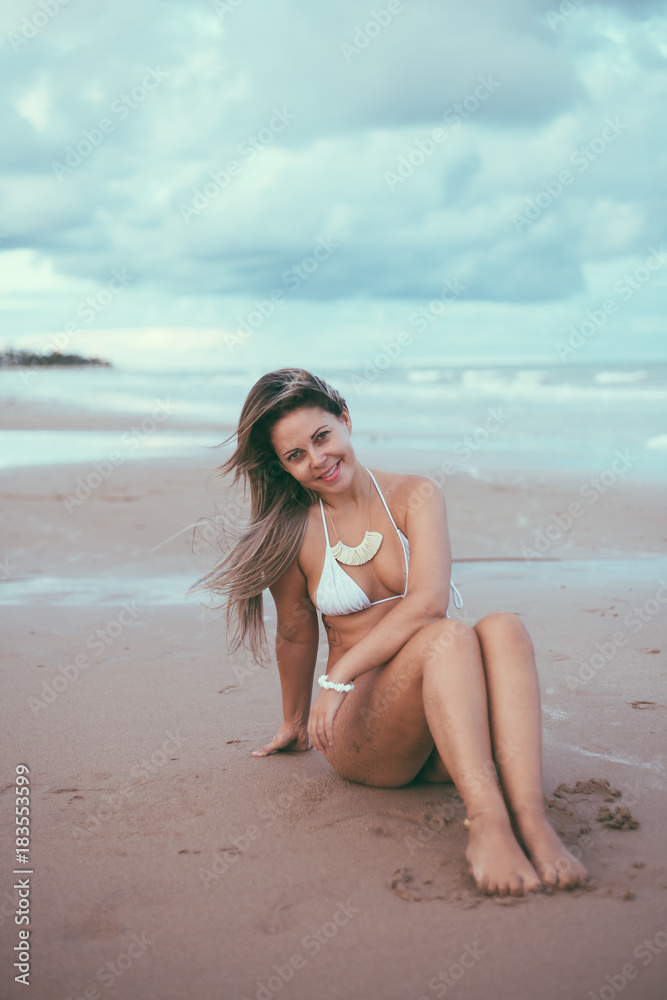 Naklejka premium Beautiful young woman on the beach at sunset