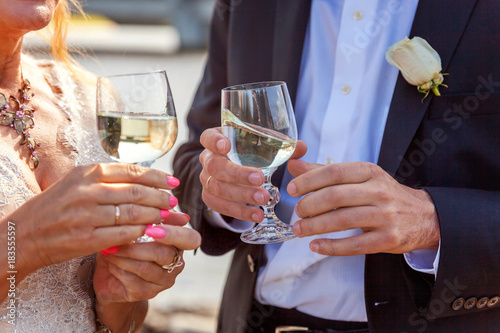 Wedding selebration. Bride and groom holding glasses of champagne making a toast, hands with glasses close up