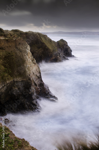 a beautiful long exposure of the waves crashing against the north cliff of Gwithian beach, Cornwall, England