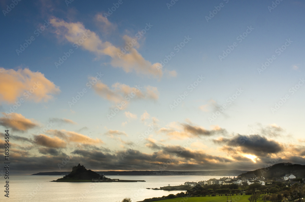 The warm sunset illuminates the passing clouds above St Michael's Mount, Marazion, Cornwall, England