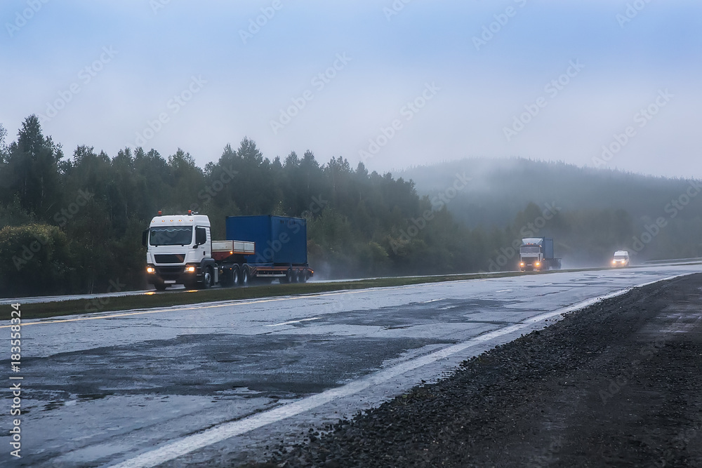trucks with containers go in the fog along the highway