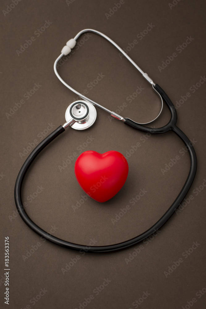 Stehoscope Around a Red Rubber Heart on Brown Background Stehoscope Around a Red Rubber Heart on Brown Background