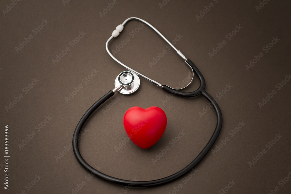 Red Rubber Heart with a Stethoscope on Brown Background Red Rubber Heart with a Stethoscope on Brown Background