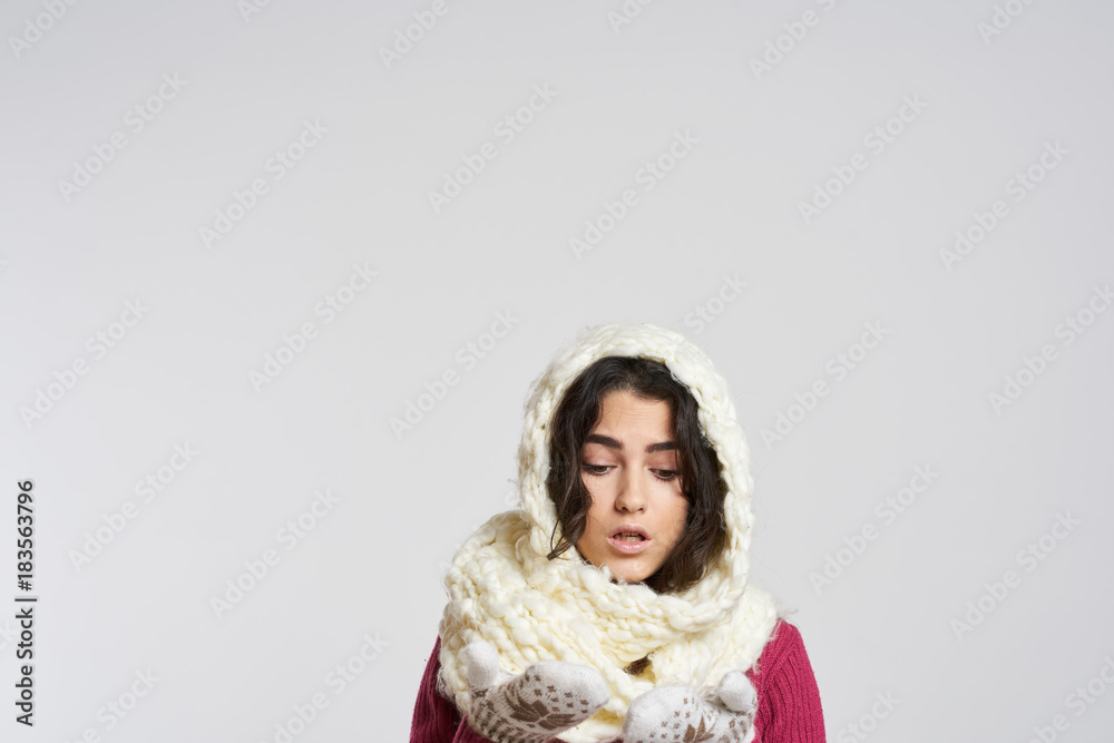 bright background, free space for copy, brunette woman in white scarf on head looking at her hands in mittens, christmas, holiday