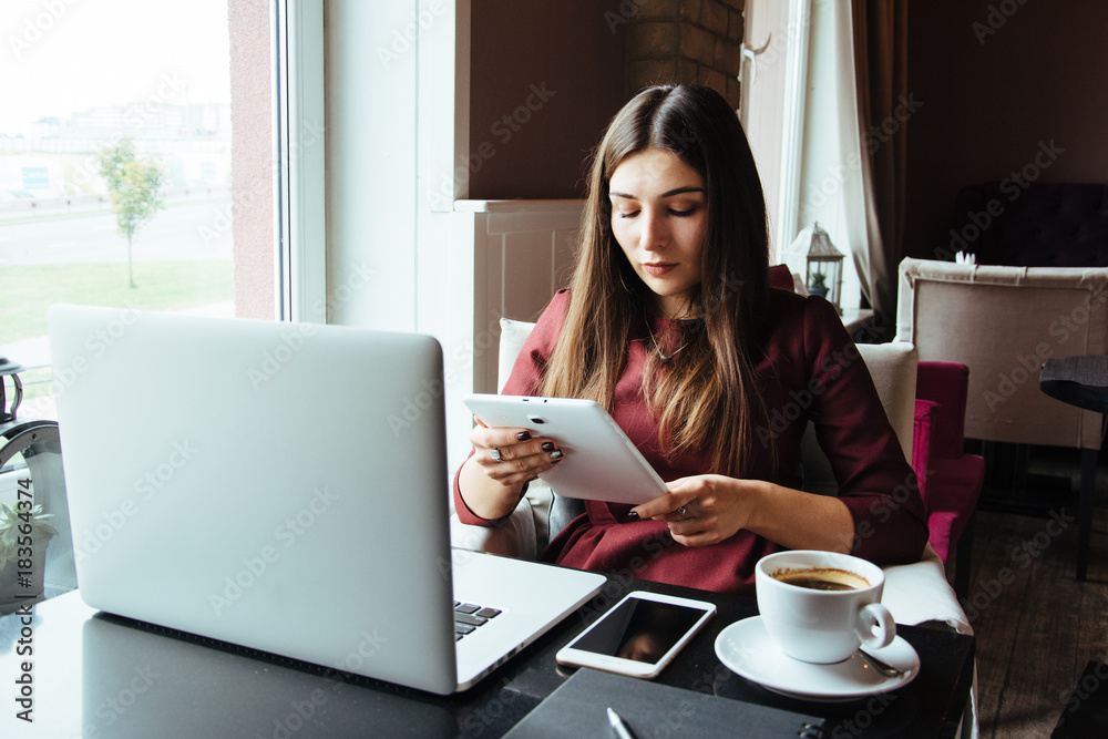Young attractive woman sitting in a cafe in the morning before her work and planning tasks for the whole day. Beautiful lady talking on the phone and discussing business strategies with her colleague. Young attractive woman sitting in a cafe in the morning before her work and planning tasks for the whole day. Beautiful lady talking on the phone and discussing business strategies with her colleague.