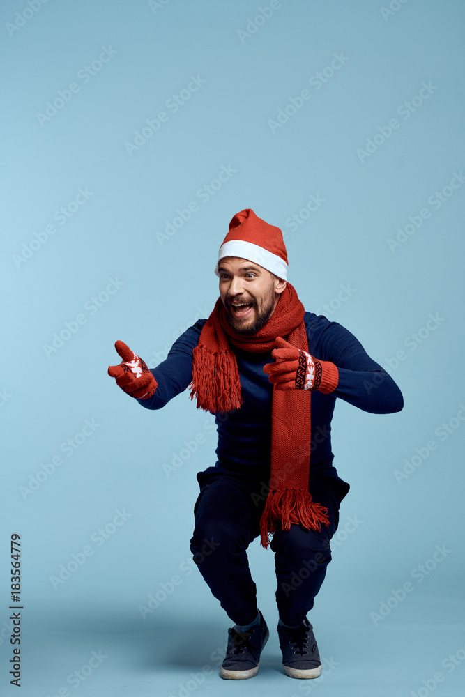 man in full growth sits, light blue background, free space for copy, Christmas hat, holiday, christmas man in full growth sits, light blue background, free space for copy, Christmas hat, holiday, christmas