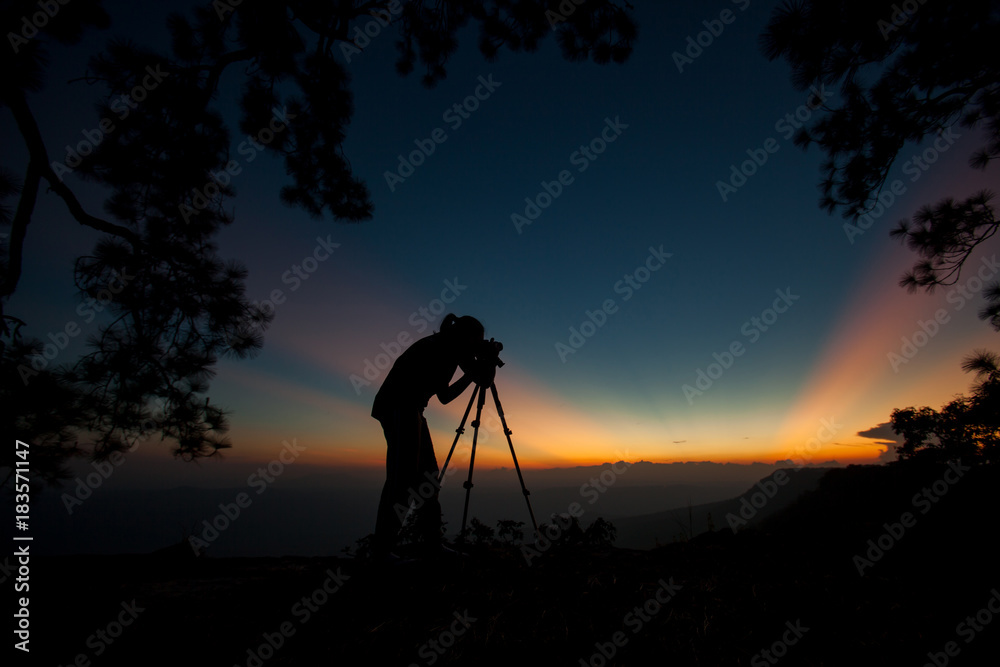 silhouette of photographer on top of mountain at sunset background