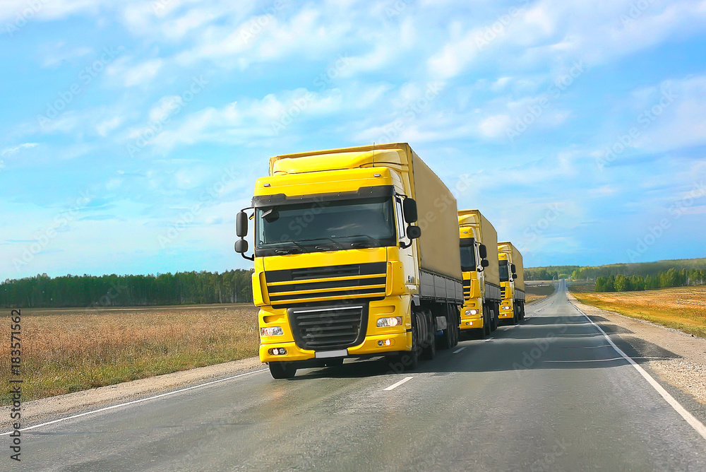 Fototapeta premium escort of yellow trucks