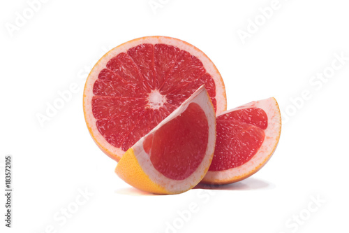 The grapefruit is cut into three pieces and lies on a white background