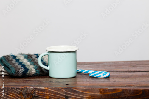 vintage bright green cup with hot tea and warm gloves on wooden table