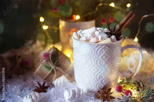 Hot chocolate in a white cup with marshmallows and Christmas gifts on the bright light background. Christmas drink.