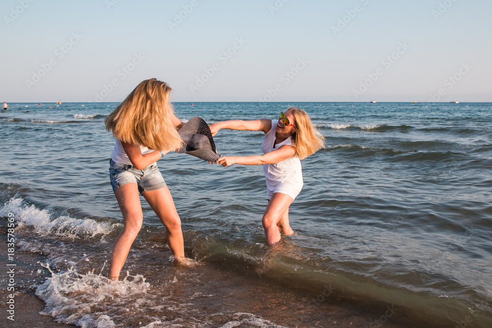 Two blond girls fighting in a water of a sea or ocean