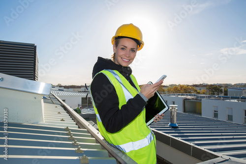 female ingineer with hardhat using electronics on construction roof photo