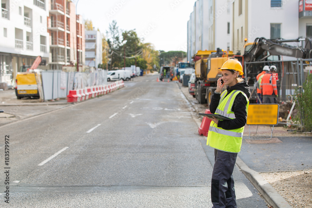 Naklejka premium female construction woman using electronics on construction site