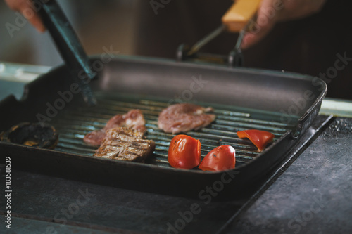 chef is frying meat and vegetables in a pan