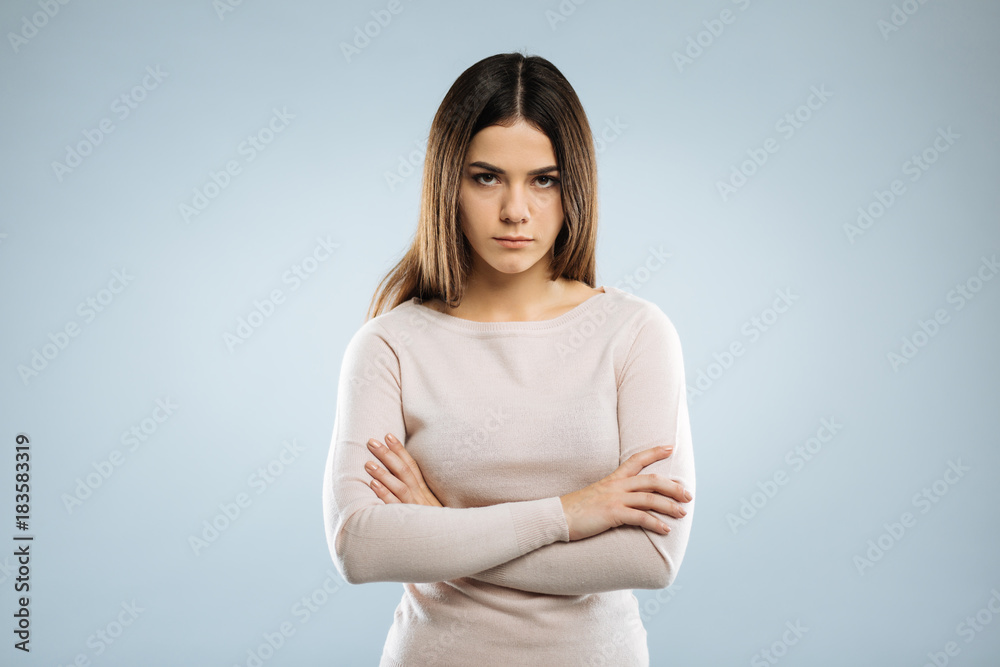 Angry with you. Concentrated young woman pressing lips and looking straight at camera, standing over grey background Angry with you. Concentrated young woman pressing lips and looking straight at camera, standing over grey background