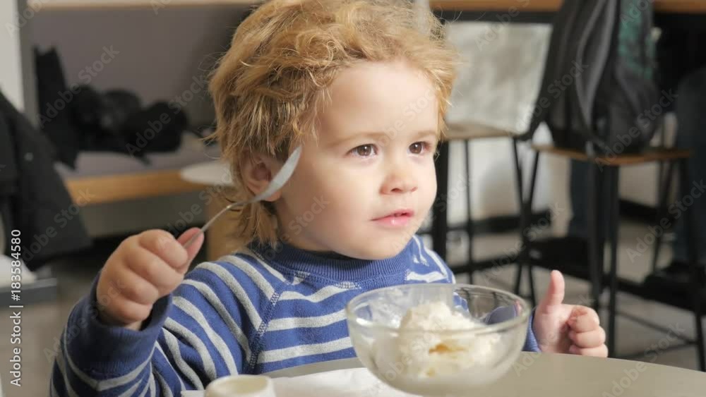 Child eats ice cream in cafe and shows a thumbs up. Mom cleans child face. Delicious dessert for toddler boy. Nutrition and carbohydrates. Cute kid and ice cream Child eats ice cream in cafe and shows a thumbs up. Mom cleans child face. Delicious dessert for toddler boy. Nutrition and carbohydrates. Cute kid and ice cream