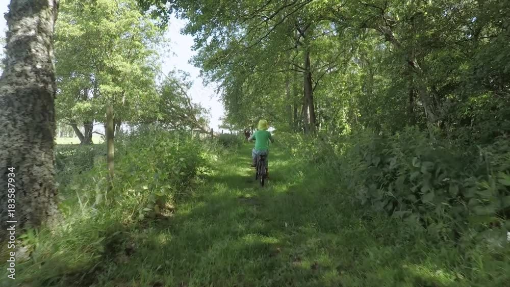 Little girl riding bicycle in green forest. Summer lifestyle moment of a happy childhood. Little girl riding bicycle in green forest. Summer lifestyle moment of a happy childhood.