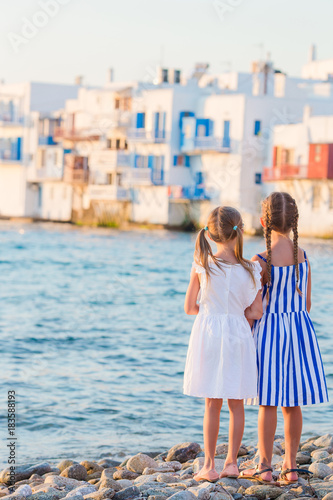 Adorable little girls at Little Venice the most popular tourist area on Mykonos island, Greece. Back view of beautiful kids look at Little Venice background. © travnikovstudio
