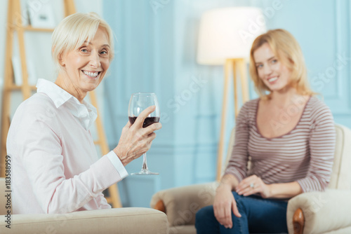 Lets celebrate. Excited emotional active senior woman feeling happy while sitting with her granddaughter and drinking red wine after hearing the news about her engagement © Viacheslav Yakobchuk