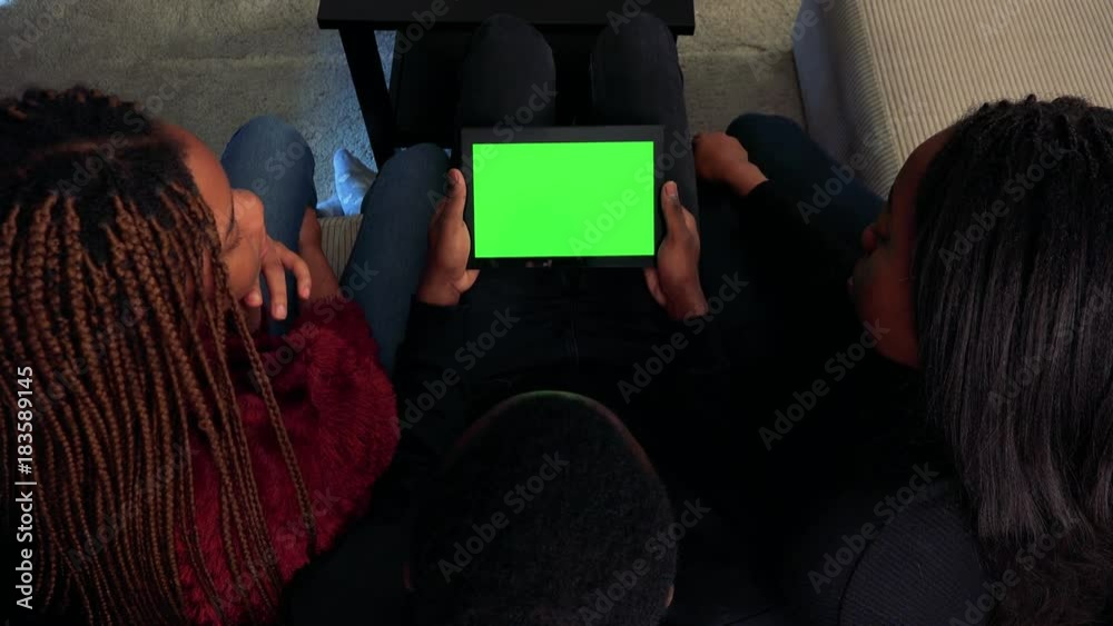 Three african friends work on tablet in living room - green screen