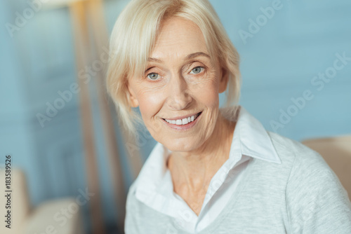 Baby boomer. Cute lovely aged woman having a good day and looking cheerful while standing and smiling happily