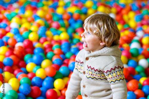 Little kid boy playing at colorful plastic balls playground
