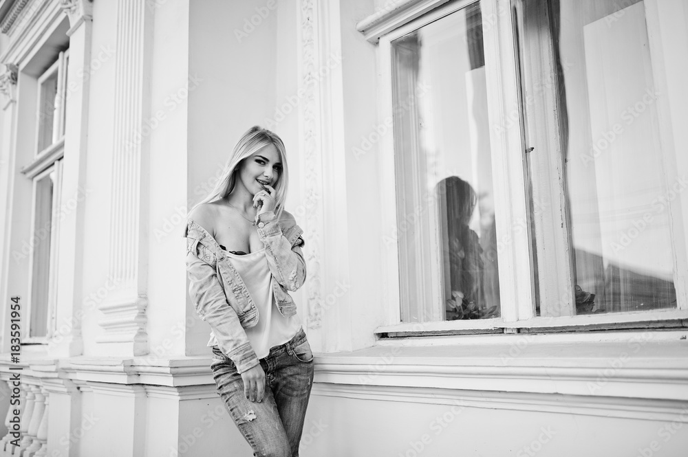 Blonde girl wear on jeans posed against old house.