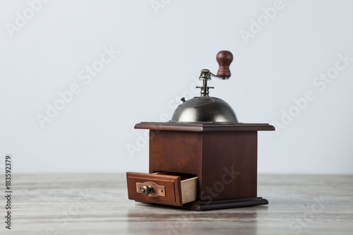 handmade wooden coffee grinder stands on a wooden table on a light background