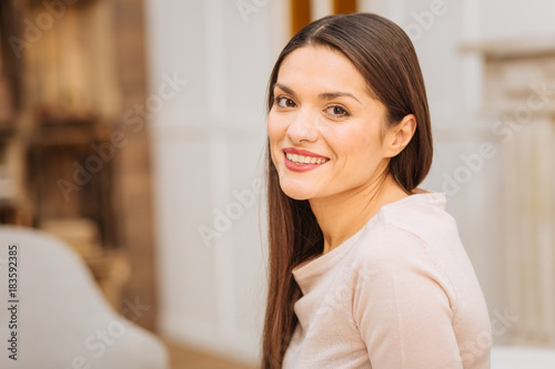 Natural posing. Nice beautiful vigorous woman listening to someone while looking straight and smiling 