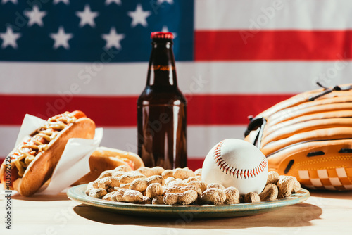 close-up view of baseball ball on plate with peanuts and beer bottle with hot dog behind