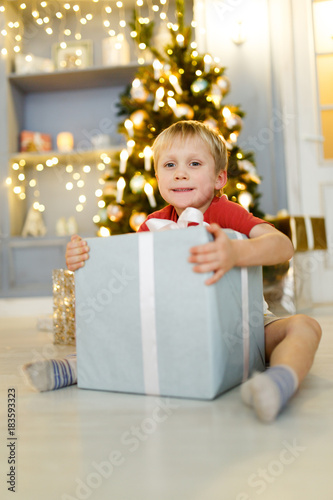 Photo of boy with gift box on background of Christmas decorations