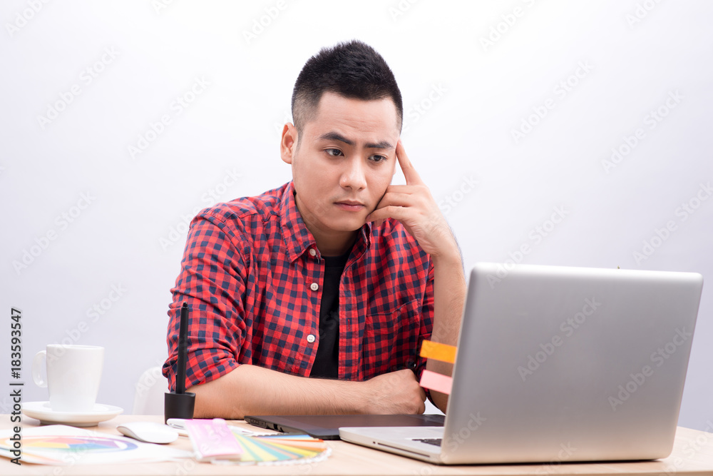 Happy designer working on his laptop in creative office