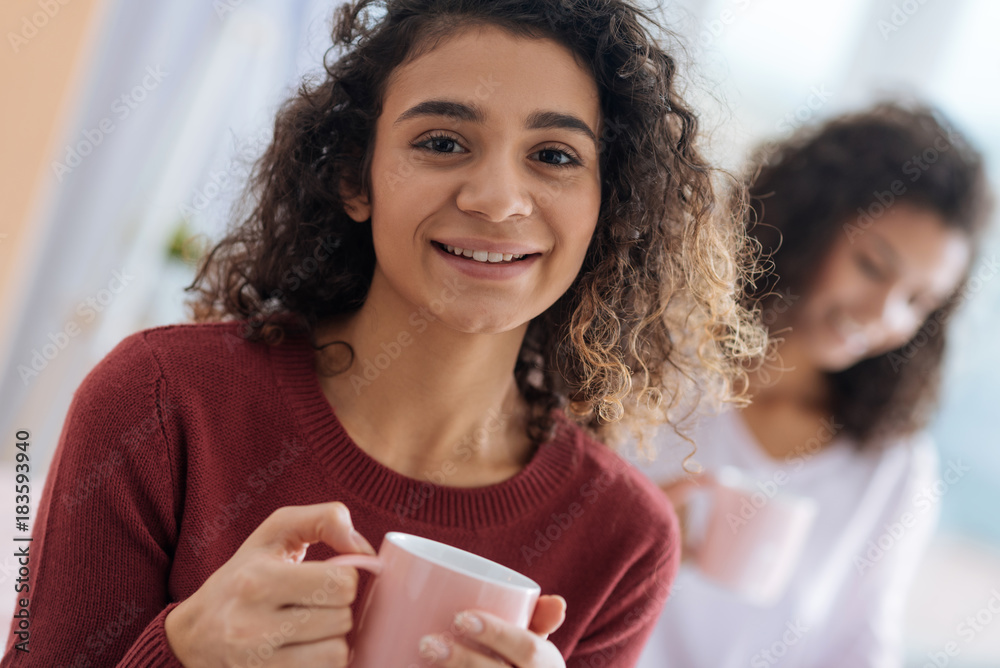 Having a lovely leisure time. Close up portrait of a pretty girl beaming while relaxing at home and enjoying her cup of warm tea. Having a lovely leisure time. Close up portrait of a pretty girl beaming while relaxing at home and enjoying her cup of warm tea.