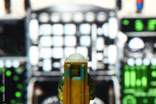 Backside of miniature model figure of airforce pilot and cockpit dashboard control panel as a background scene.
