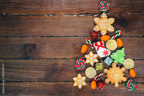 Christmas tree with candy from gingerbreads, sweets and traditional decorations on an old wooden brown background. Merry Christmas concept. Free space