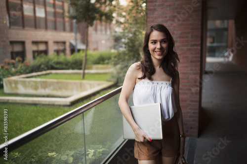 Portrait of young smiling woman holding laptop