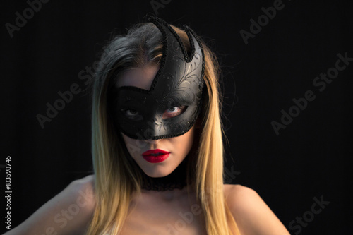 Mystic blonde woman in mask on dark background