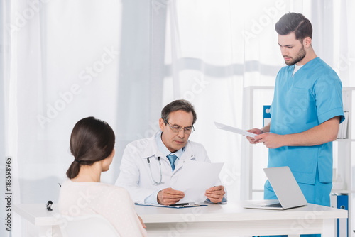 doctor reading female patient documents at clinic