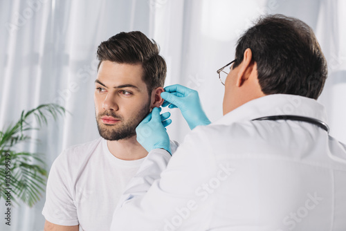 doctor examining male patient ear